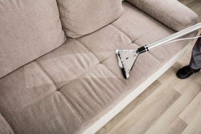 A-man-using-steam-carpet-cleaner-on-the-beige-couch-1024x683.jpg