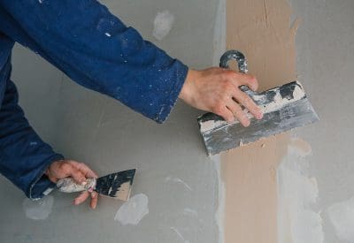 plasterer-man-works-plastering-two-trowels-plasterboard-blue-uniform.jpg